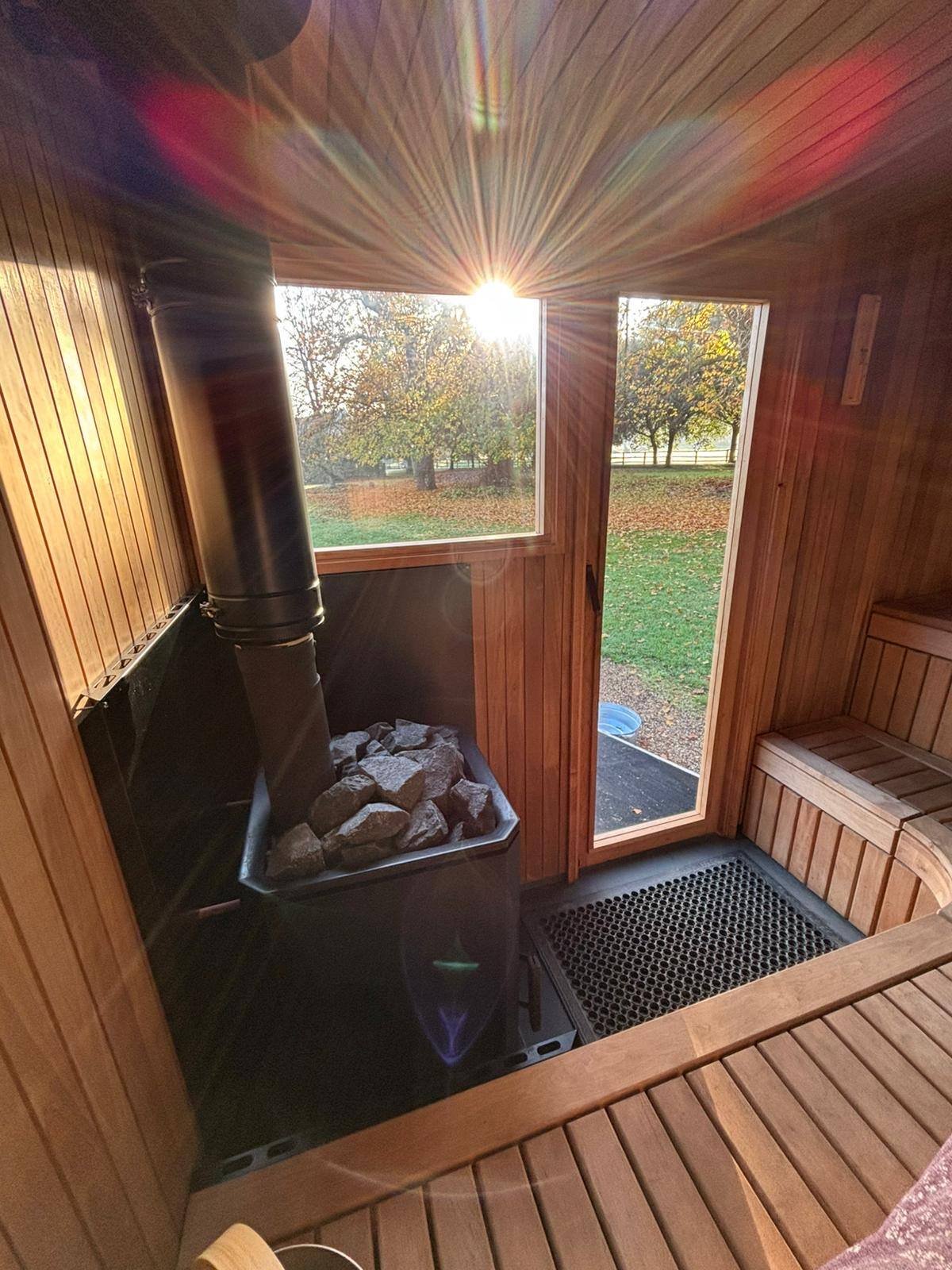 Timber sauna interior with wood-fired stove and benches